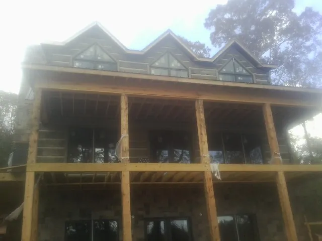 Dormers and porch framing on a large log home under construction — Roof Coating work by our crew in Herman